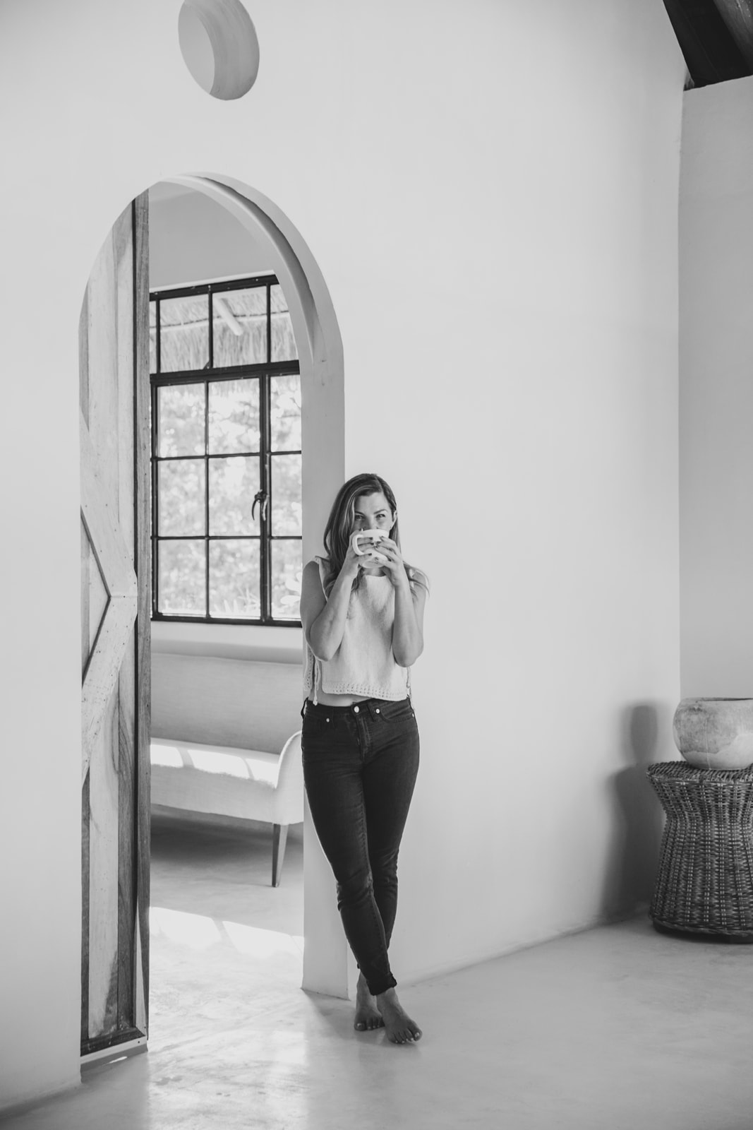 Kierstan Streber standing in a plaster archway holding a cup of coffee